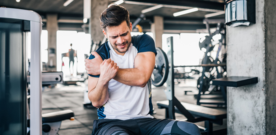 Male-individual-at-the-gym-holding-his-shoulder-in-pain