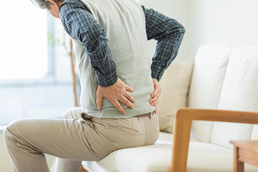Male-sitting-on-couch-and-holding-his-lower-back-in-pain