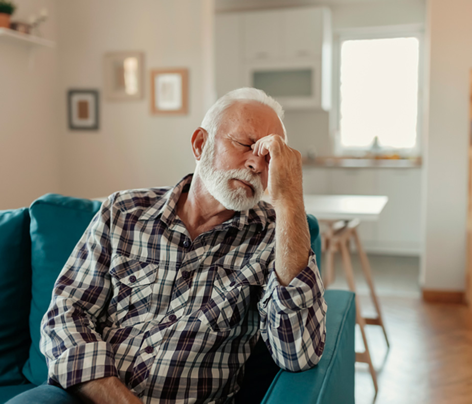 Senior-man-experiencing-migraine-headache-while-sitting-on-sofa